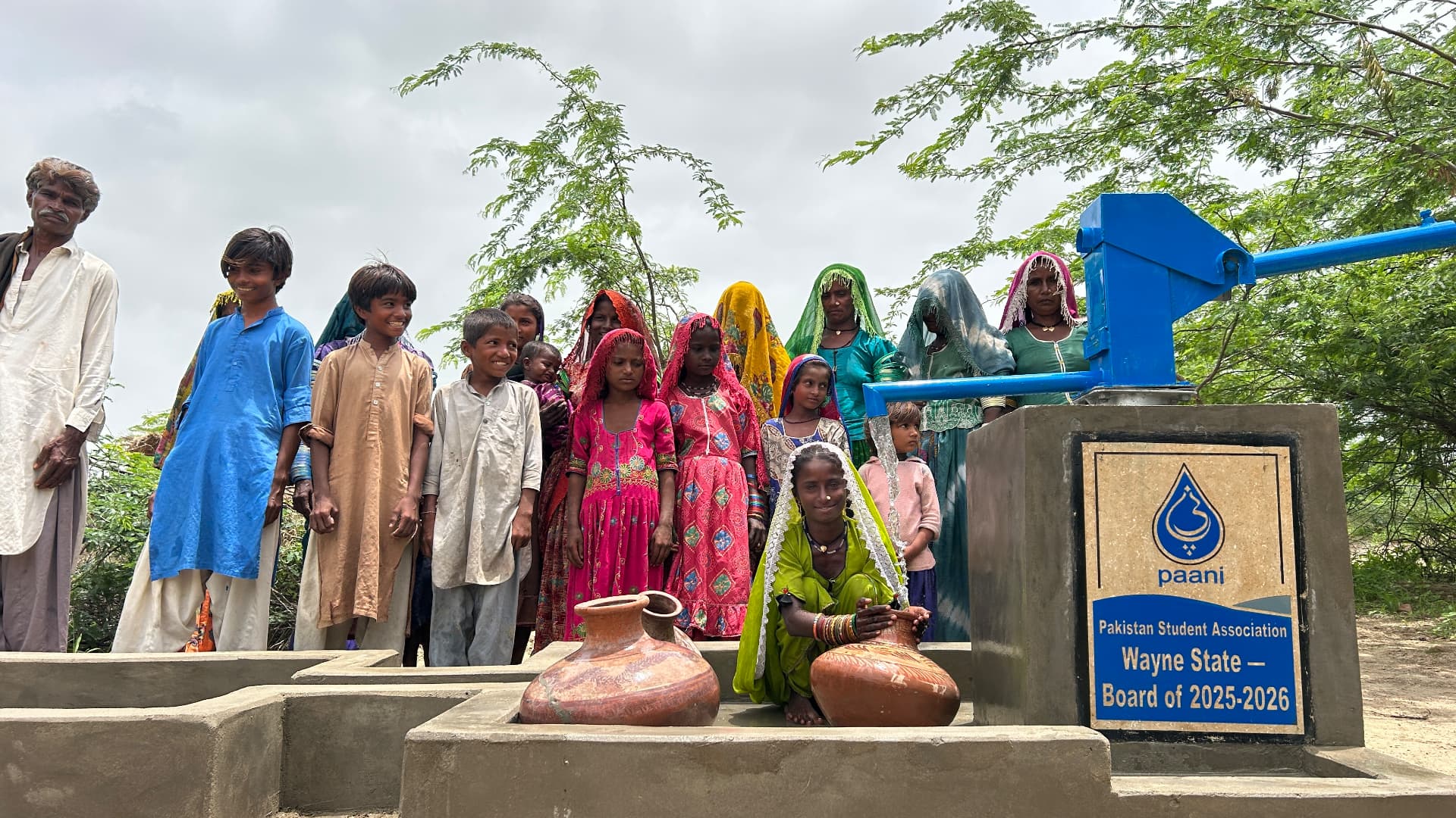 Villagers gathered around the new hand pump with the Wayne State PSA plaque