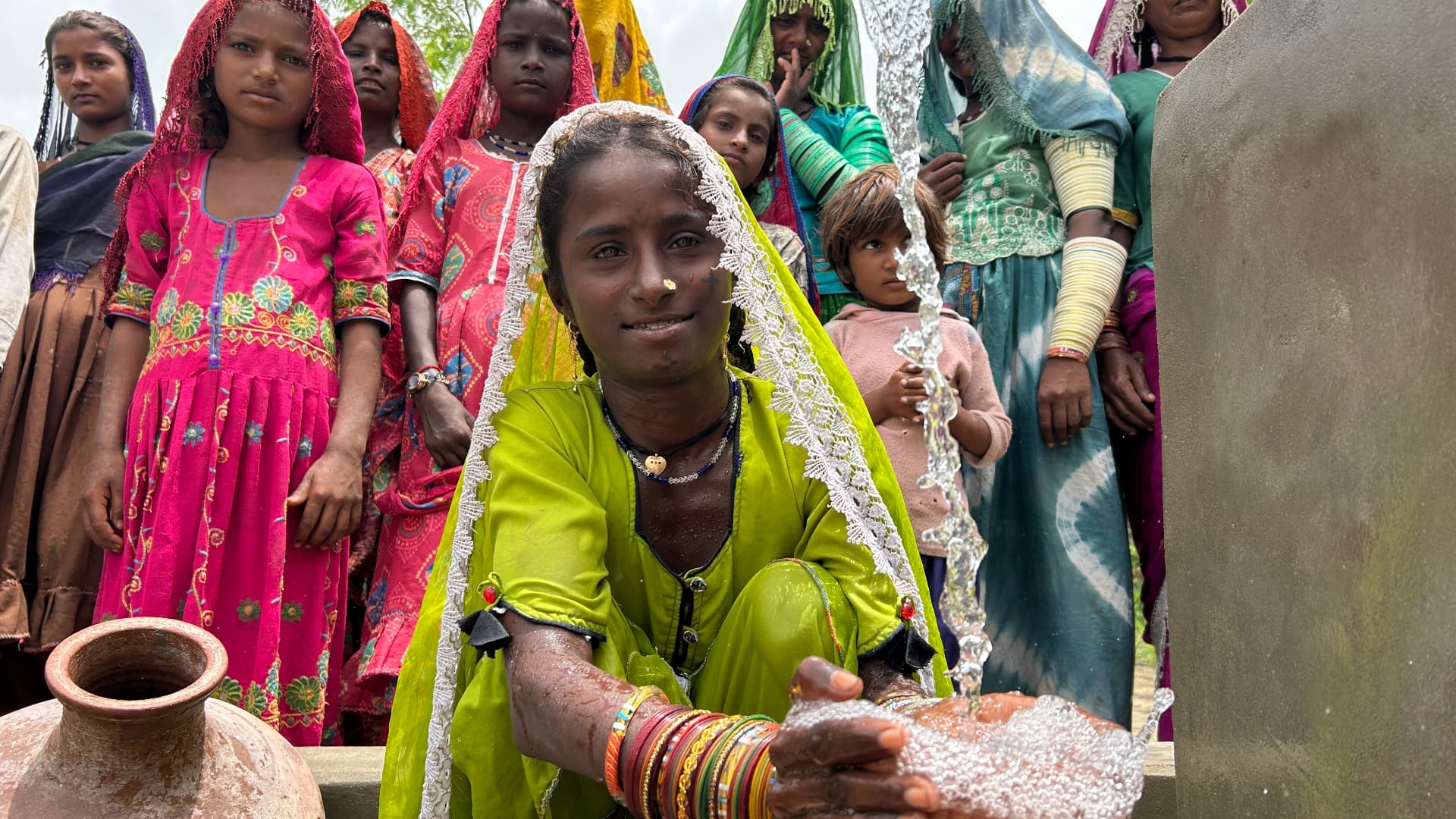 A young girl catching clean water flowing from the new well