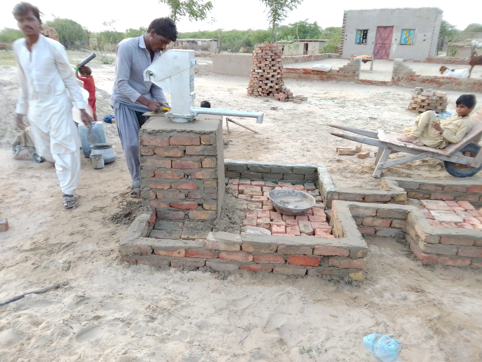 Masons building the brick platform around the pump