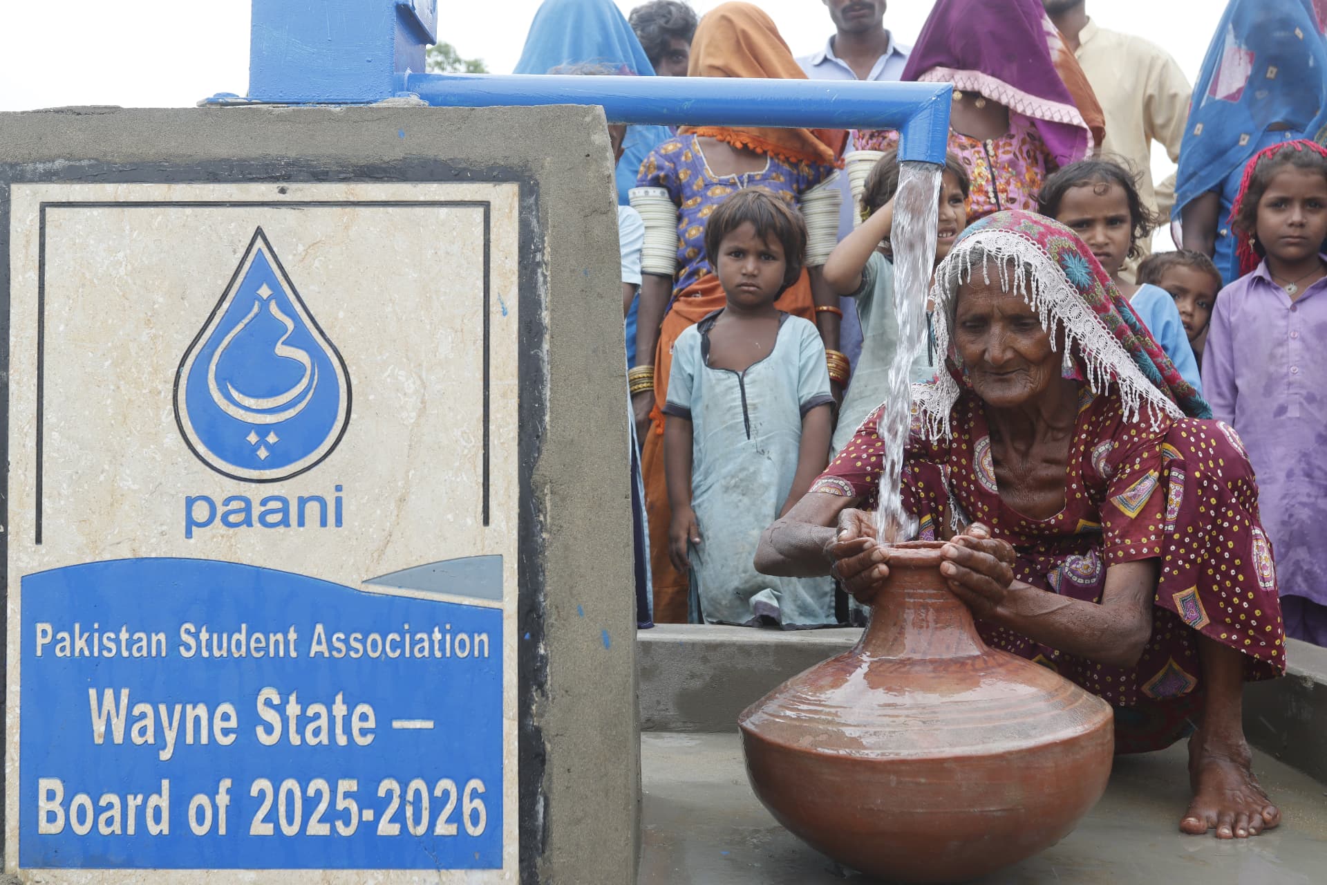An elder filling a clay pot from the new water pump